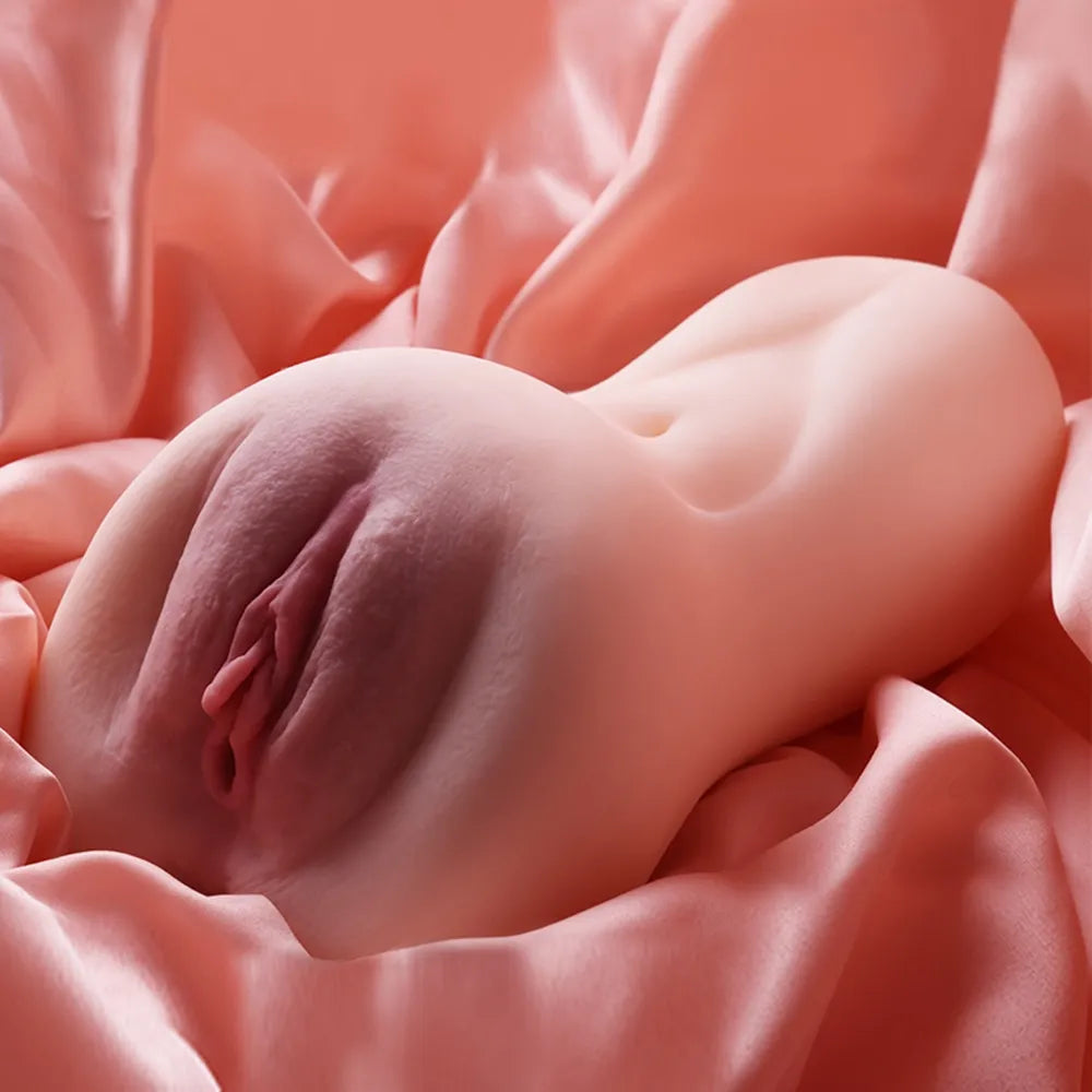 Realistic female anatomy replica with soft skin texture, nestled on satin fabric for intimate use.