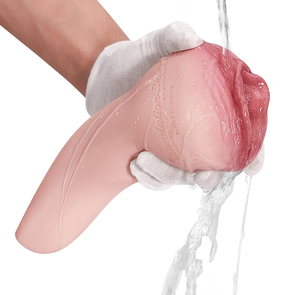 Pink realistic male masturbator with textured interior, being rinsed under water, held in gloved hand